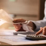 primer-plano-economista-que-usa-calculadora-mientras-revisa-facturas-impuestos-oficina